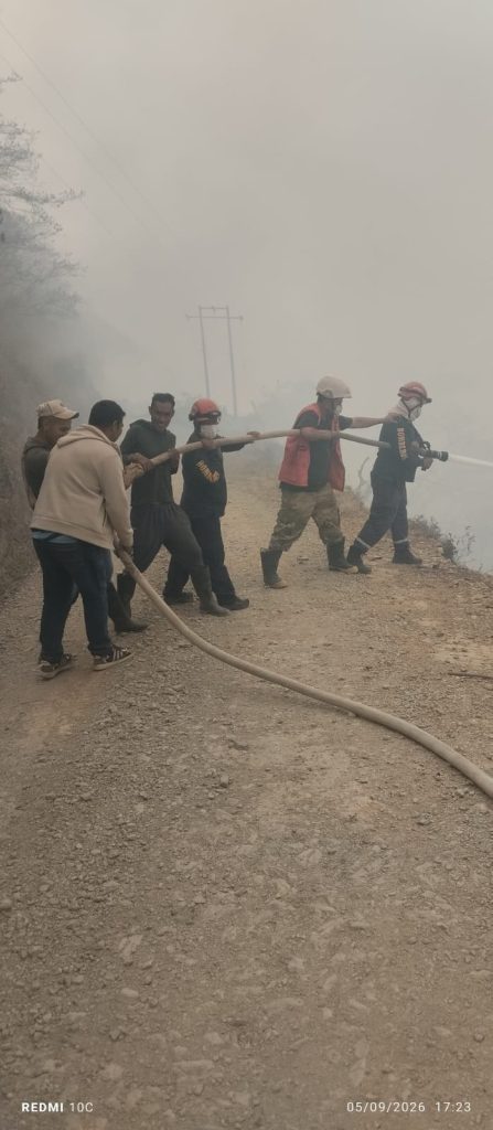 Bomberos desplazan una manguera en medio del humo durante las labores de control.