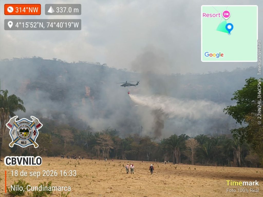 Panorámica del incendio forestal en el cerro de la vereda La Palmita, donde se observa una extensa columna de humo cubriendo la zona montañosa y personal en el área de la emergencia.