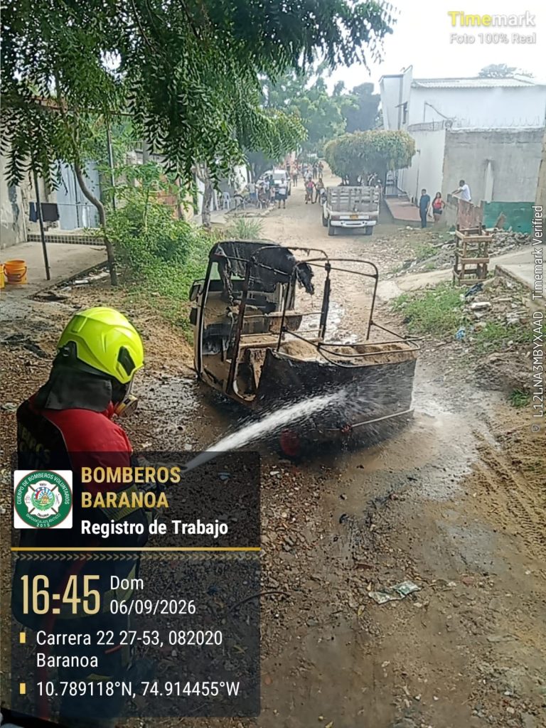 Bombero realiza labores de extinción y enfriamiento sobre el vehículo afectado.