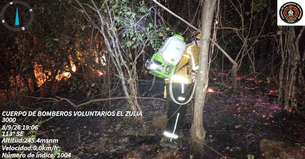 Bombero de El Zulia realiza labores nocturnas de control con un equipo de espalda entre vegetación y focos activos.