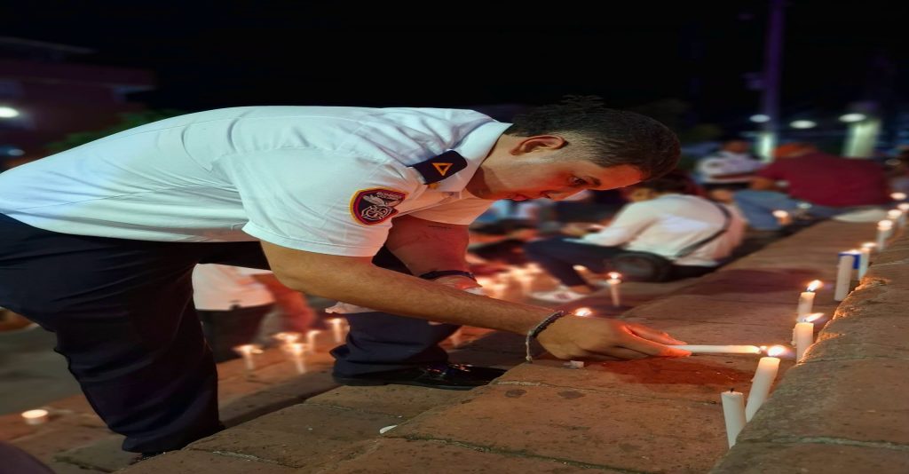 Integrante del Cuerpo de Bomberos enciende una vela durante el acto conmemorativo.