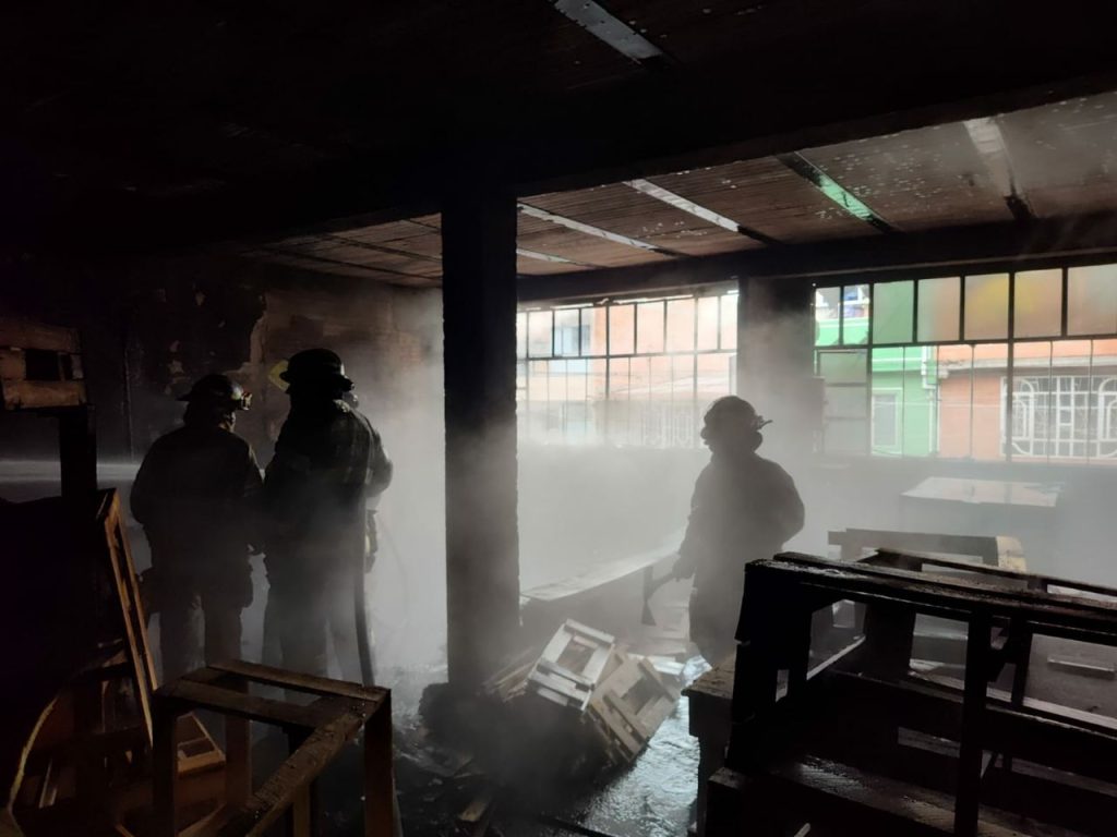 Unidades bomberiles realizan labores de control y extinción del incendio en el interior de la fábrica de muebles en Soacha.